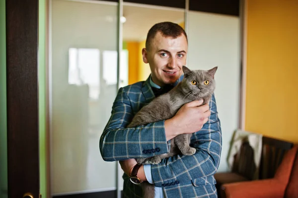 Knappe bruidegom poseren met een beetje leuk katje in zijn kamer. — Stockfoto