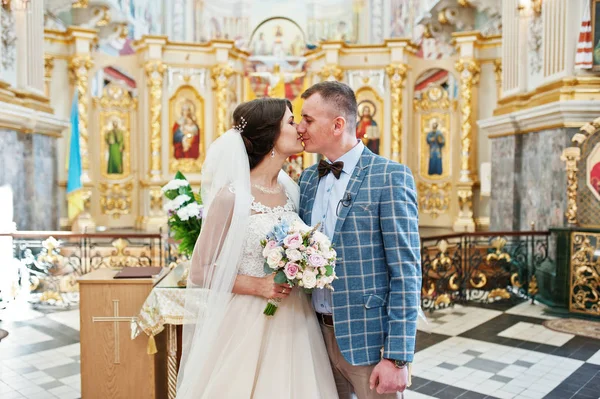 Unga attraktiva underbara bröllop par kyssar i kyrkan en — Stockfoto