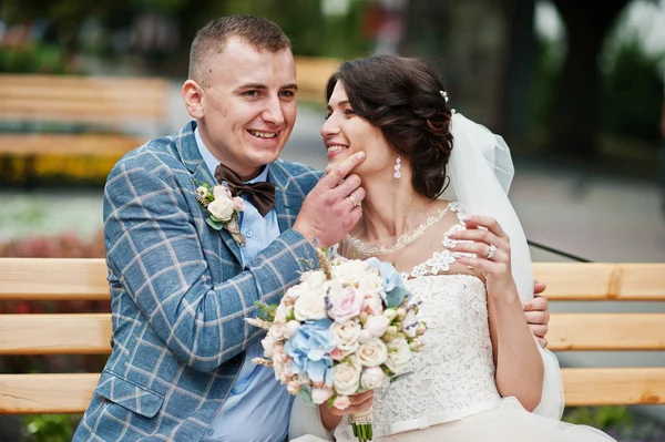 Beau couple de mariage assis sur un banc dans le centre ville o — Photo