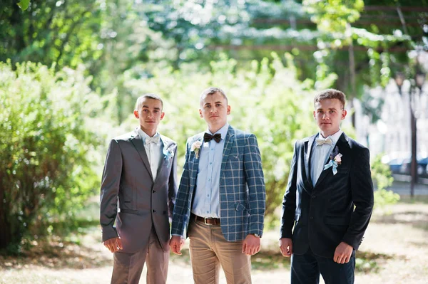 Knappe bruidegom met zijn groomsmen wandelen in het park naast th — Stockfoto