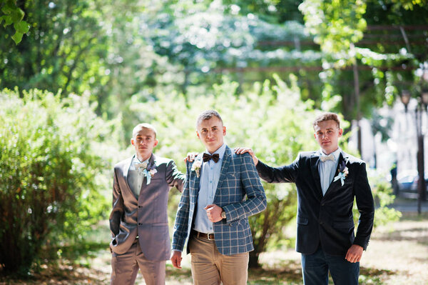 Handsome groom with his groomsmen walking in the park next to th