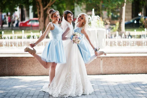 Beautiful bride with bridesmaids posing next to a fountain in th — Stock Photo, Image