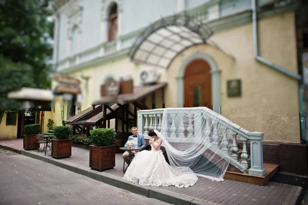 Casal lindo jovem sentado à mesa de vidro com um — Fotografia de Stock