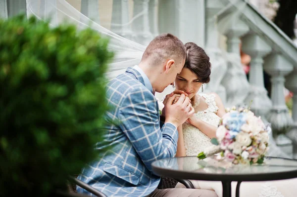 Jeune couple magnifique de mariage assis près de la table en verre avec un — Photo