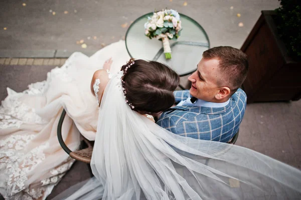 Joven pareja hermosa boda sentado junto a la mesa de cristal con un — Foto de Stock