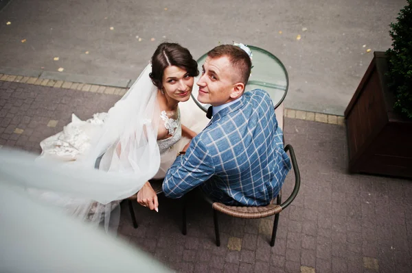 Jeune couple magnifique de mariage assis près de la table en verre avec un — Photo