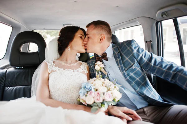 Gorgeous wedding couple kissing in a car. — Stock Photo, Image