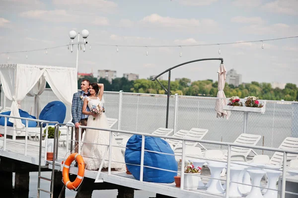 Belo casal andando em um cais em um dia de casamento ensolarado . — Fotografia de Stock