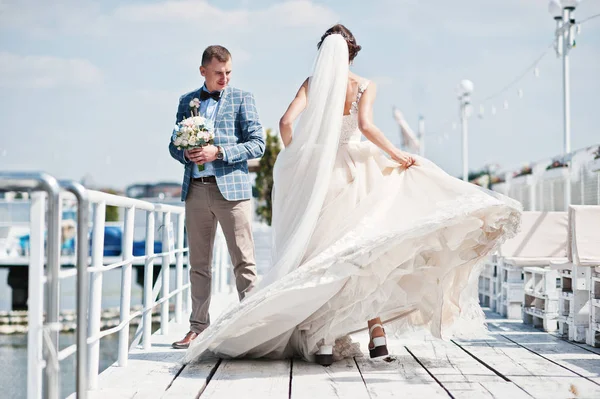 美丽的夫妇在阳光明媚的婚礼那天在码头上行走. — 图库照片