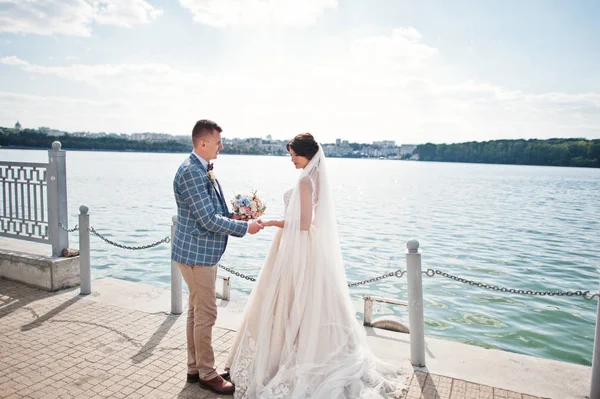 Prachtige bruidspaar lopen op de oever van het meer op een zonnige dag. — Stockfoto