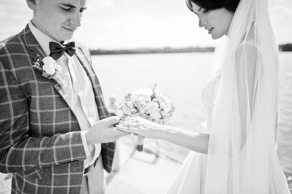Atemberaubendes Hochzeitspaar, das an einem sonnigen Tag am Ufer des Sees spaziert. schwarz — Stockfoto