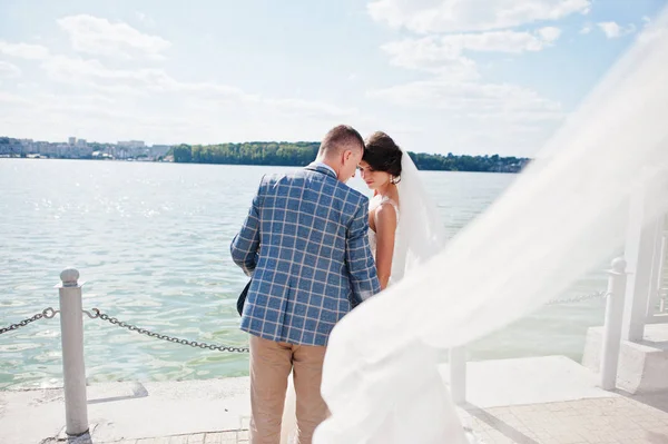 Casal de casamento impressionante andando ao lado do lago em um dia ensolarado . — Fotografia de Stock