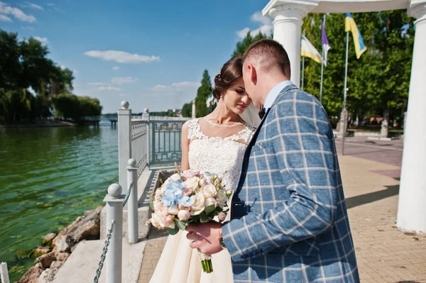 Impresionante pareja de boda caminando junto al lago en un día soleado . — Foto de Stock