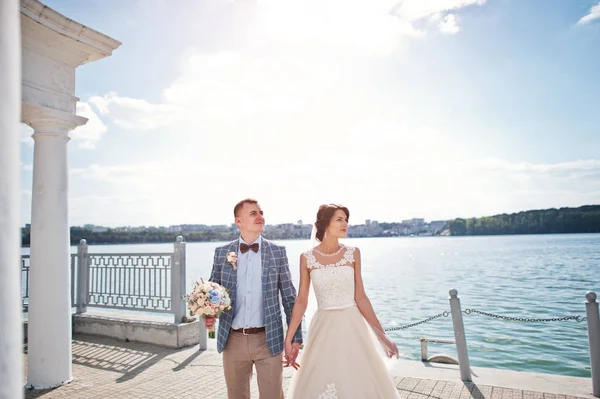 Casal de casamento impressionante andando ao lado do lago em um dia ensolarado . — Fotografia de Stock