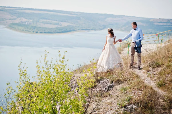 Fantastic wedding couple standing on the edge of rocky precipice — Stock Photo, Image