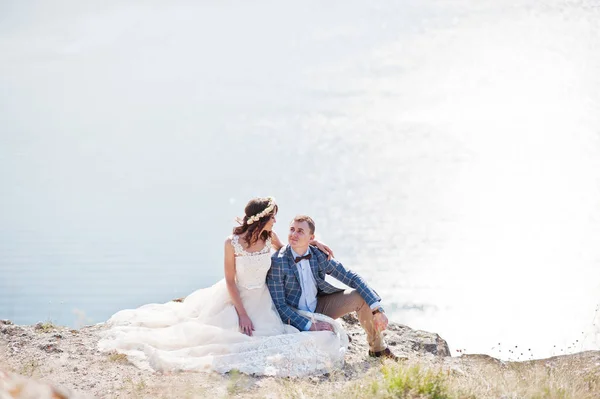 Wspaniałe ślubu Młoda para siedzi na skraju klifu w — Zdjęcie stockowe
