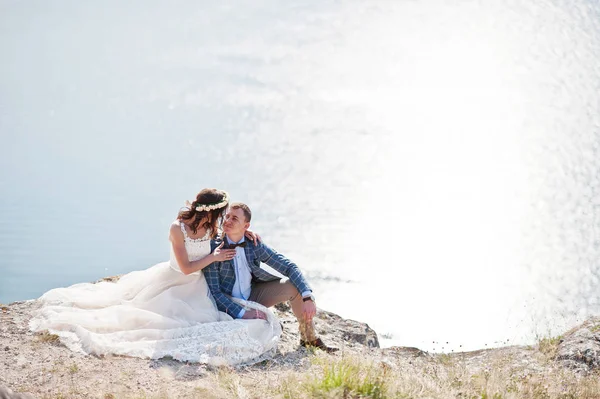 Prachtige jonge bruidspaar zittend op de rand van de klif w — Stockfoto