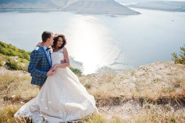 Bonita noiva e noivo beijando na borda do penhasco rochoso com um — Fotografia de Stock