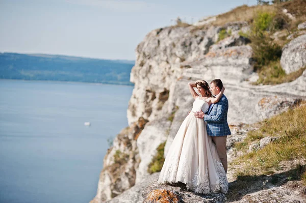 Fantastic wedding couple standing on the edge of rocky precipice — Stock Photo, Image