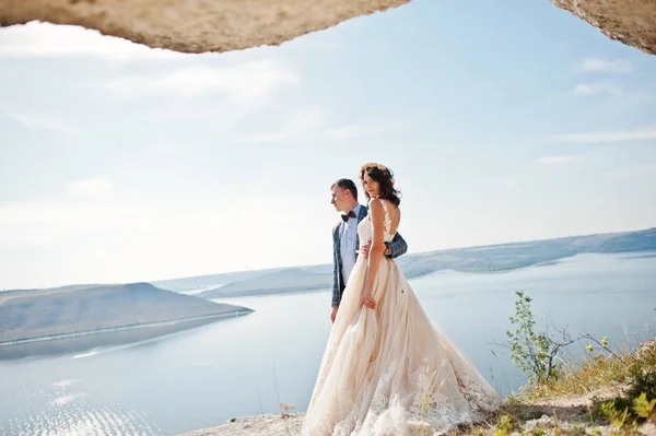 Gorgeous wedding couple posing next to the cave with breathtakin — Stock Photo, Image