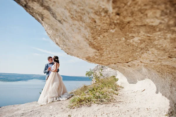 Hermosa pareja de boda posando junto a la cueva con breathtakin —  Fotos de Stock