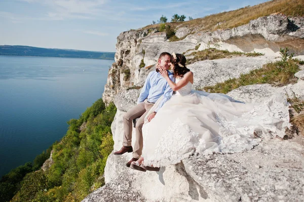 Impresionante joven pareja de boda sentado en el borde del acantilado w — Foto de Stock