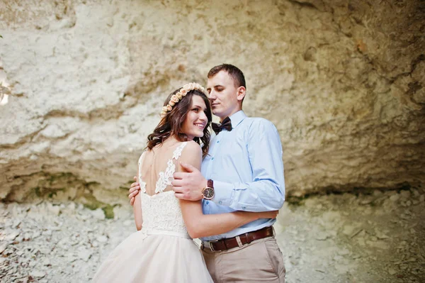 Beautiful bride with handsome groom posing next to the cave in f — Stock Photo, Image