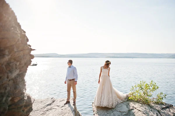 Fabulosa pareja de boda de pie en el acantilado junto a un gran roc — Foto de Stock