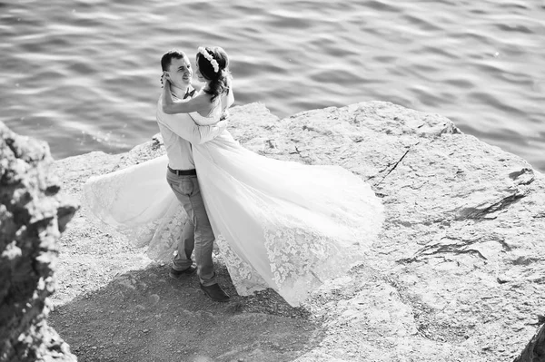 Newly married couple dancing on the rocky cliff with a view of a — Stock Photo, Image