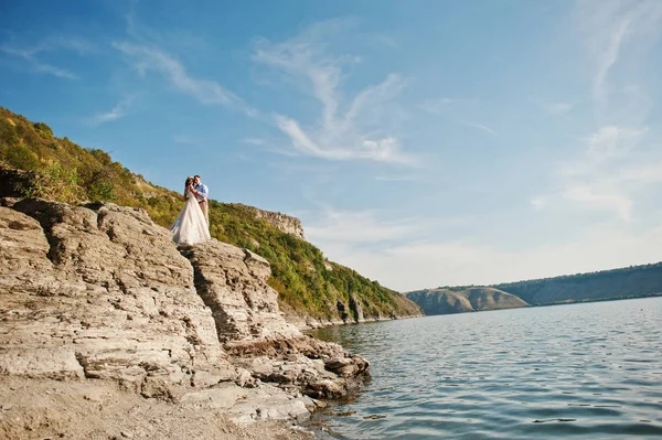 Удивительные невеста и красивый жених целуются и обнимаются на скале — стоковое фото