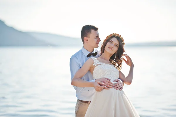 Amazing young couple holding hands on the lake shore on their su