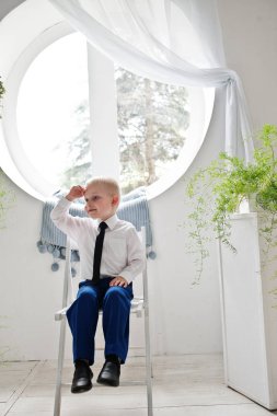 Beyaz koltukta oturan sevimli bir küçük çocuk portresi