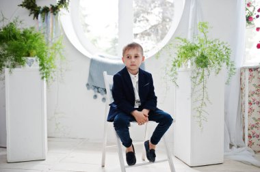 Beyaz koltukta oturan sevimli bir küçük çocuk portresi