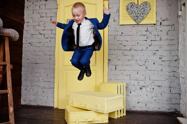 Retrato de un pequeño niño lindo saltando de las cajas amarillas en th — Foto de Stock