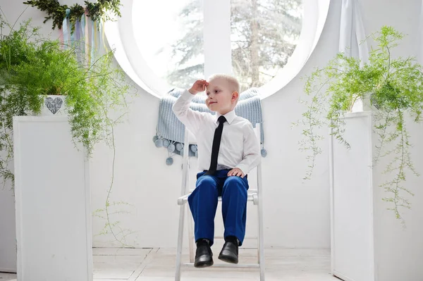 Beyaz koltukta oturan sevimli bir küçük çocuk portresi