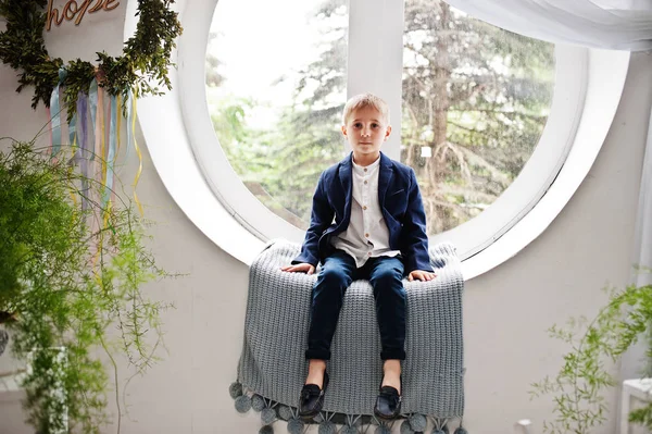 Csodálatos kisfiú ízlésesen öltözött, ül a kerek ablak — Stock Fotó