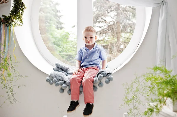 Increíble niño vestido con estilo sentado en la ventana redonda — Foto de Stock