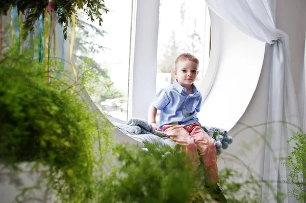 둥근 창에 앉아 옷을 입고 세련 된 어린 소년을 놀라운 — 스톡 사진