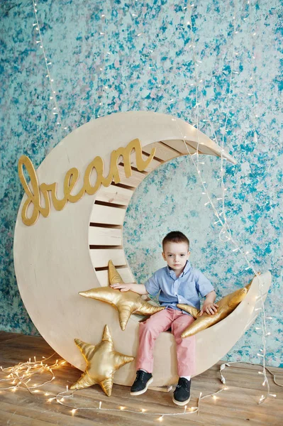 Lindo pequeño guapo chico posando en artificial luna decoración whi — Foto de Stock