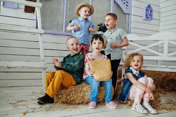 Preschool kids posing outside the house with straw in the rural