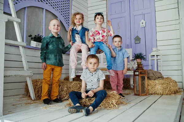 Preschool kids posing outside the house with straw in the rural