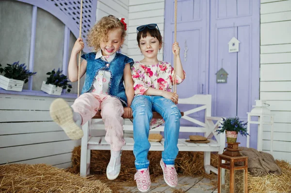 Dos niñas sentadas en el columpio fuera de la casa con str — Foto de Stock