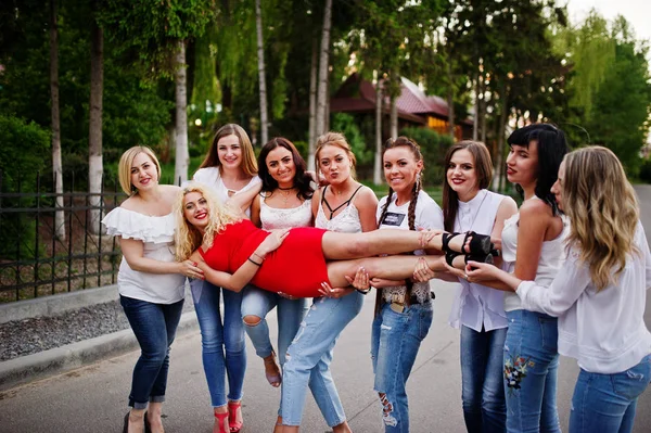 Louco companhia de damas de honra segurando noiva em vestido vermelho no p — Fotografia de Stock