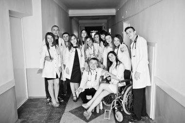 Çılgın genç doktorlar tekerlekli sandalyede poz tarafından eğleniyor 