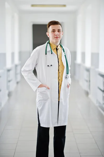 Pohledný a sebevědomý mladý doktor v bílém plášti s stethosco — Stock fotografie