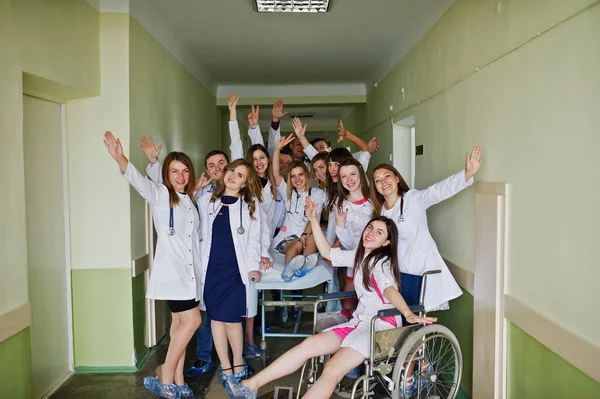 Locos médicos jóvenes que se divierten posando en una silla de ruedas en el —  Fotos de Stock