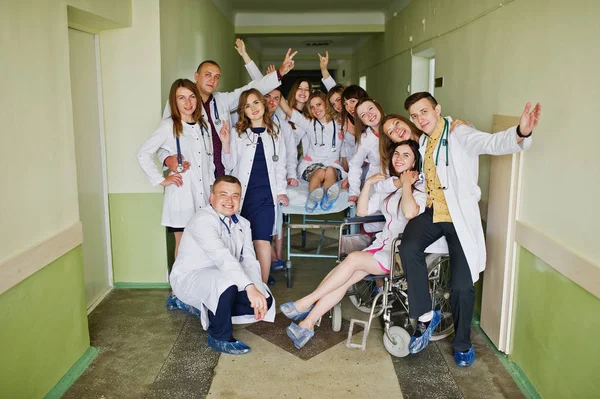 Сумасшедшие молодые врачи веселятся, позируя на инвалидной коляске в — стоковое фото
