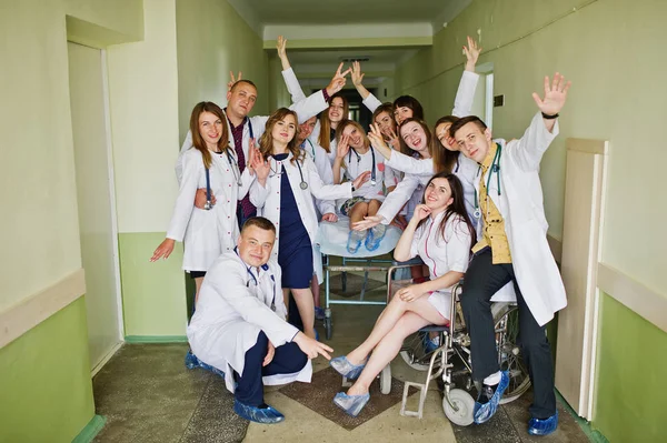 Locos médicos jóvenes que se divierten posando en una silla de ruedas en el —  Fotos de Stock