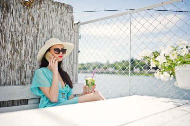 Tatlı genç bayan şapka ve bir kokteyl birimi ile güneş gözlüğü takıyor