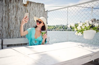 Tatlı genç bayan şapka ve bir kokteyl birimi ile güneş gözlüğü takıyor